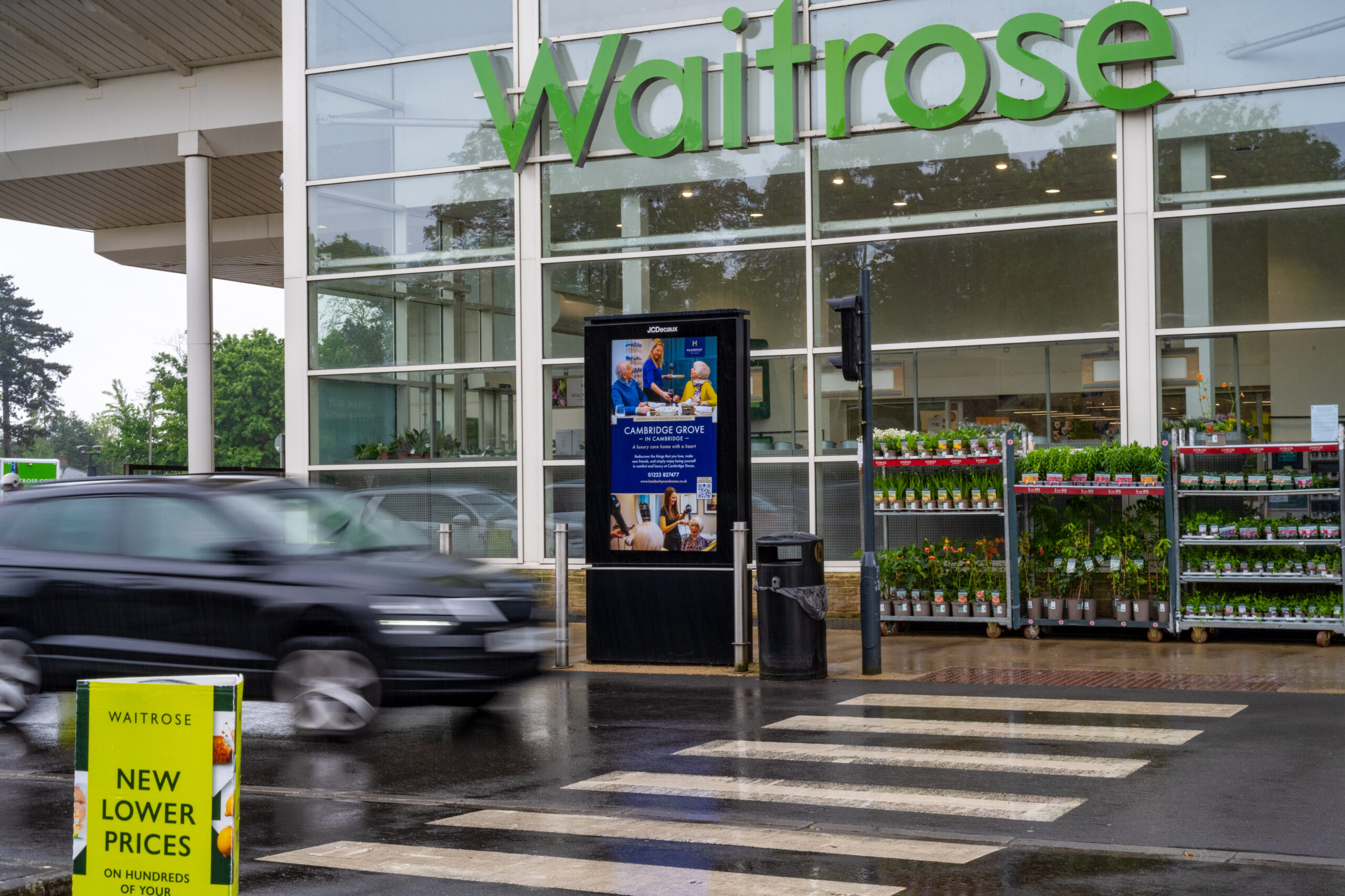Digital advertising screen outside a Waitrose supermarket promoting retail media advertising to grocery shoppers