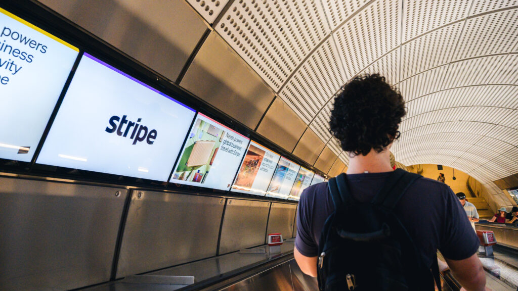 Commuters viewing digital escalator advertising on the London Underground